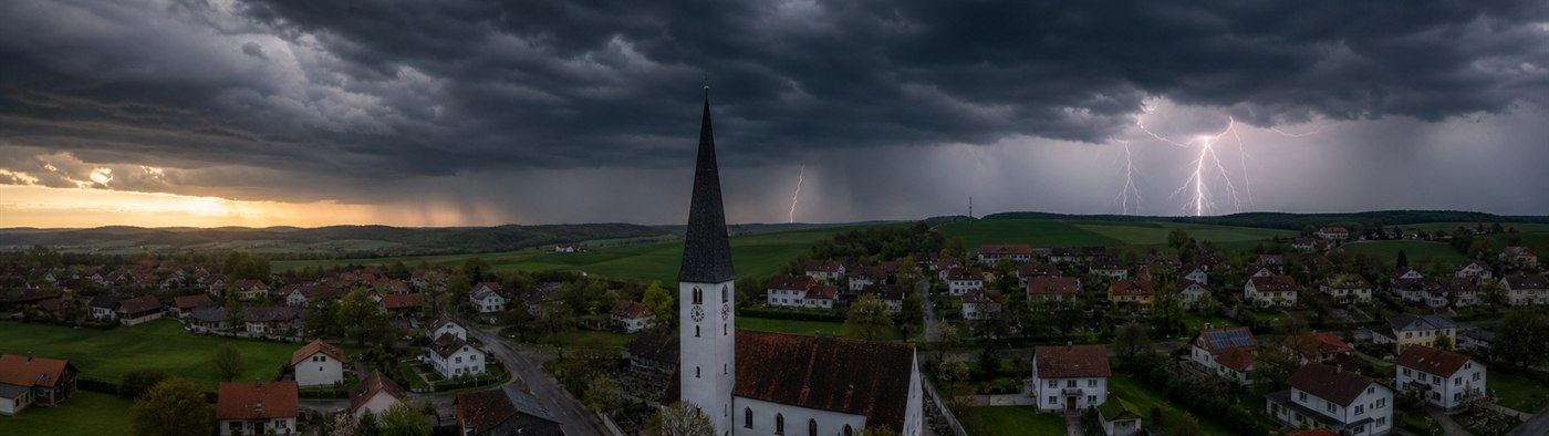 Gewitterwolken mit Blitzen über Mamming als Symbol für aktuelle Warnungen